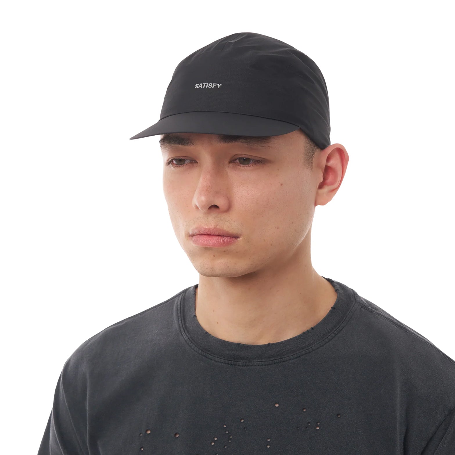 Satisfy Pertex® 3L Rain Cap in Black — front view worn on model showing low-profile fit, flexible brim and black Pertex® Shield Air construction with stealth-reflective Satisfy logo
