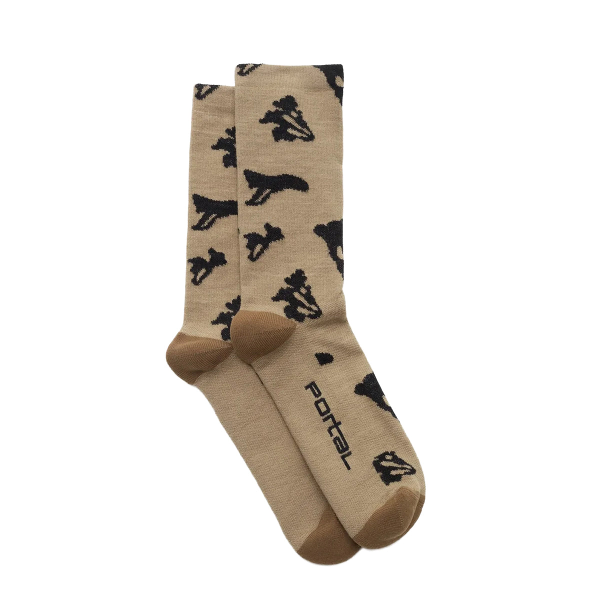 A pair of Ritual Merino Socks Greige by Portal, crafted from tan merino wool with dark brown toes and heels. These durable active socks feature a playful black dinosaur pattern and “PORTAL” printed near the toe, combining everyday comfort with a fun touch for your outfit.