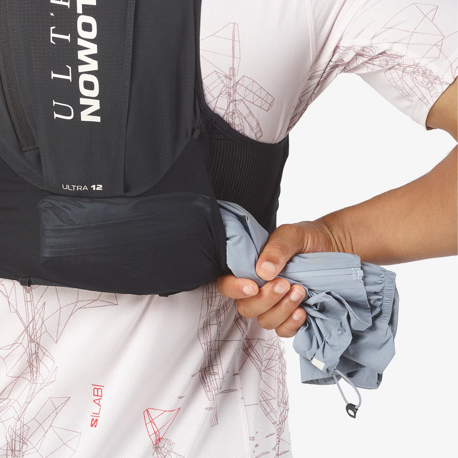 Salomon S/LAB Ultra 12 Set Running Vest Black back view showing running jacket being pulled from tunnel back pocket storage