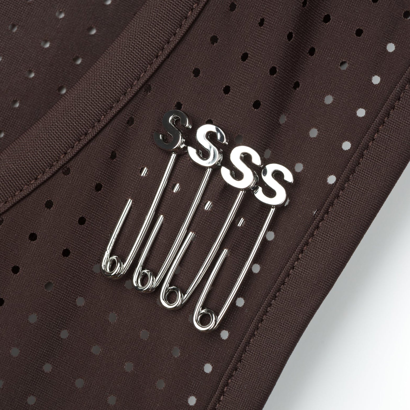 Satisfy Space-O™ Singlet in Deep Mahogany — closeup showing four ©Satisfy S-Pins positioned through laser perforations for race-day bib fastening
