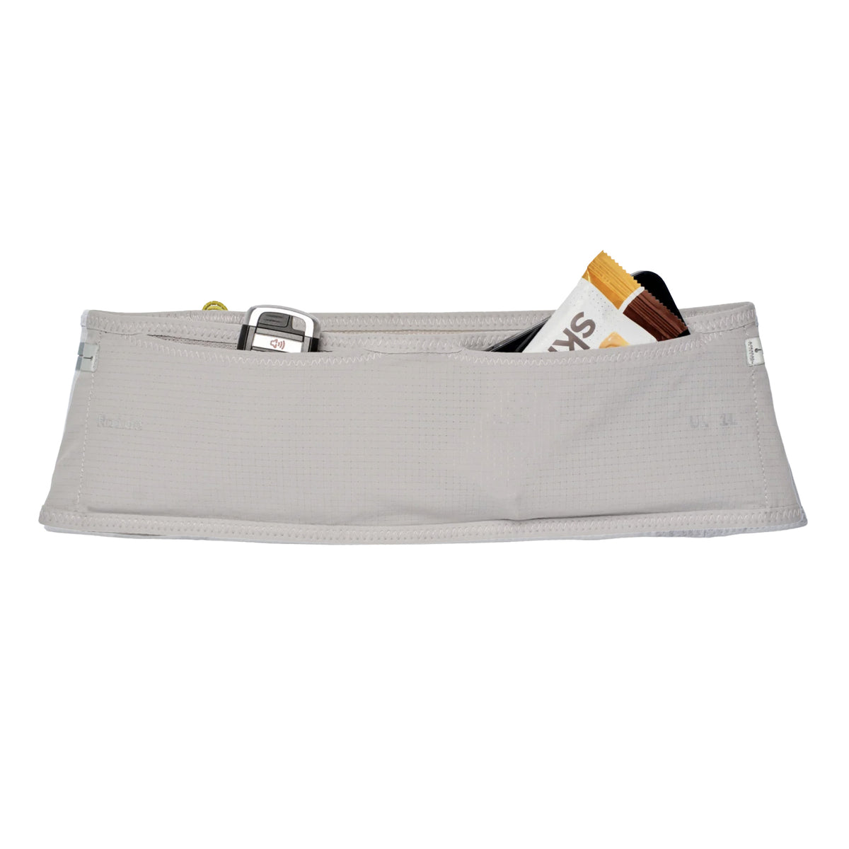 The Raide UL 1L Running Belt Stone is a light gray fabric pouch with visible outer pockets holding a flip phone and two snack bars, featuring a no-bounce suspension for added stability—perfect as a compact running belt, isolated on a white background.