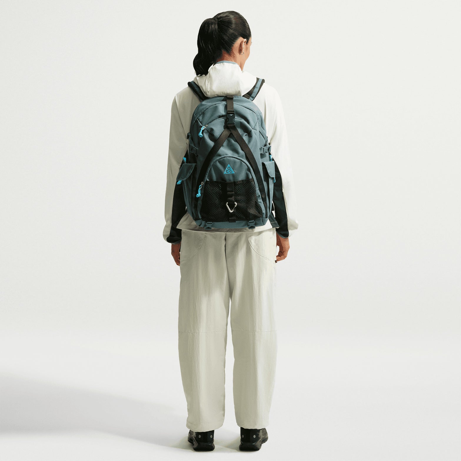 Nike ACG Dolomiti women's trousers in Sea Glass / Black — full body back view worn on model showing sea glass water-repellent nylon, elastic waistband and snap secure back pocket with embroidered logos