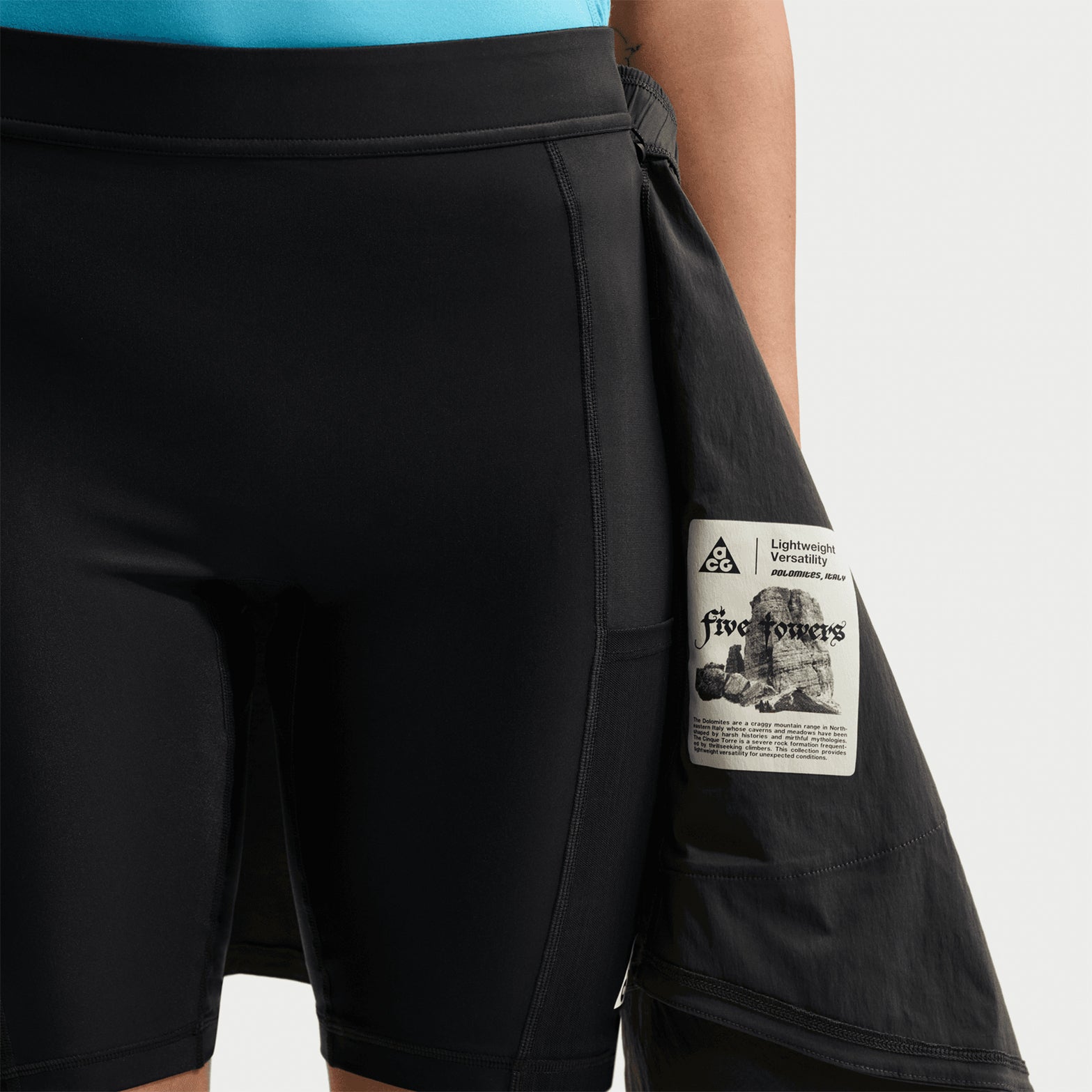 Women's Nike ACG Five Towers Skort Anthracite Summit White showing skirt flap pulled apart to reveal biker shorts underneath with convertible button system for three-way styling options