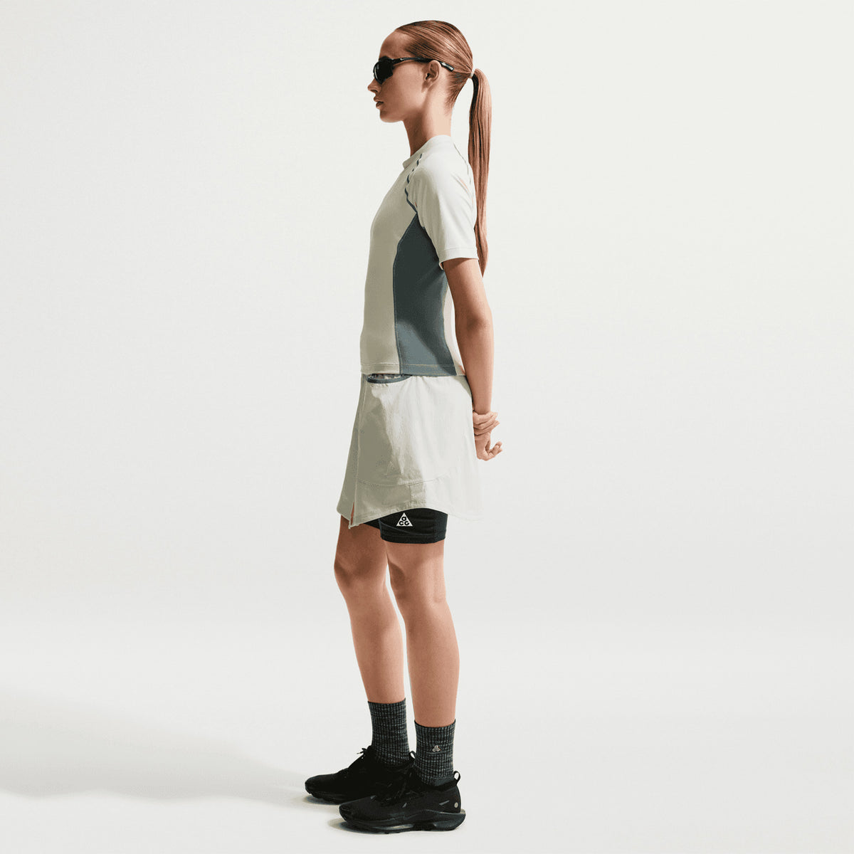 Women's Nike ACG Five Towers Skort Sea Glass Spruce Fog Summit White side view on female runner showing convertible design with side buttons, Dri-FIT moisture management and big drop-in pockets for trail running essentials