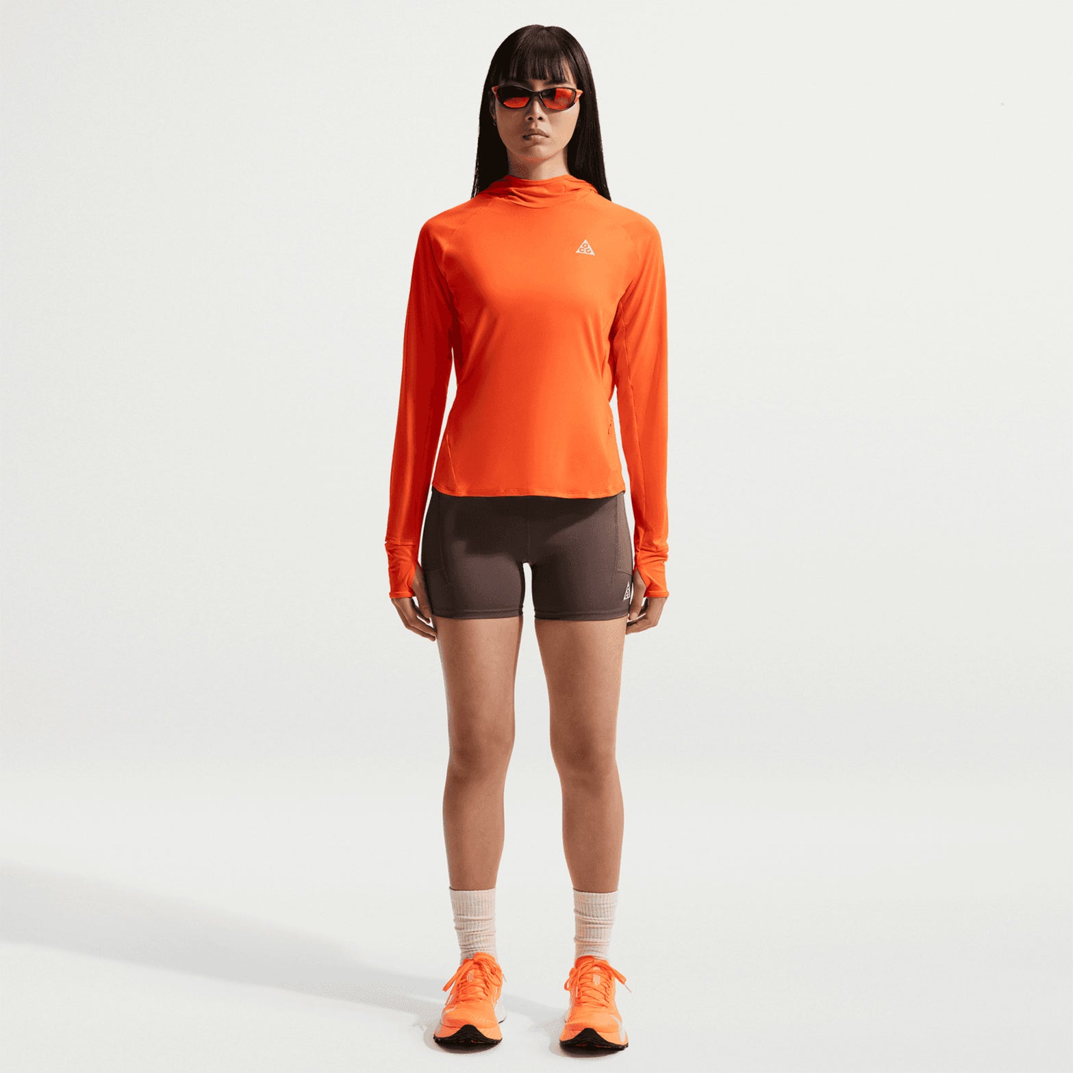 Women's Nike ACG High-Waisted 4 Inch Short Tights Ironstone Cave Stone Summit White front full body view on female runner showing 4-inch tight fit with eight-pocket storage system and reflective ACG logo