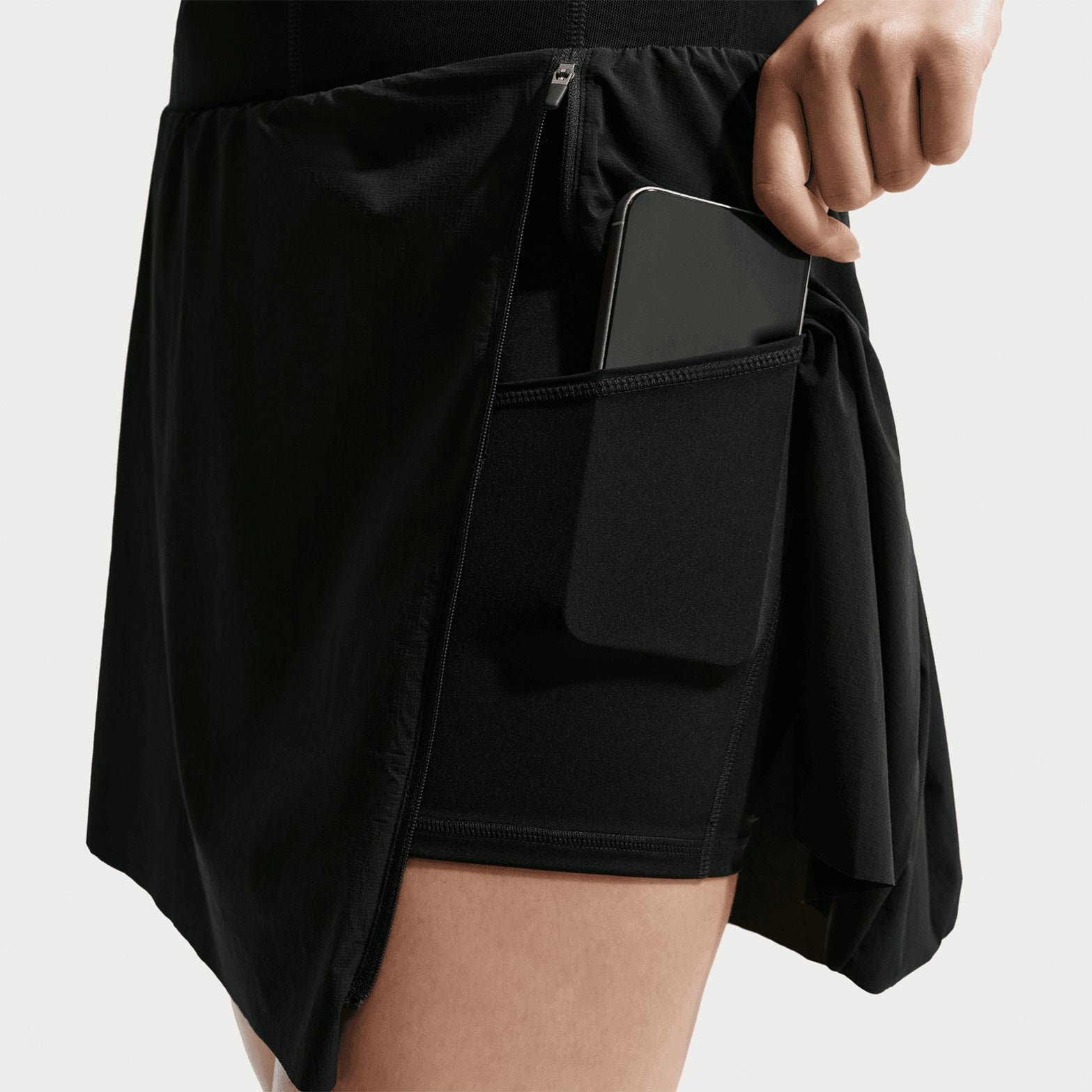 Women's Nike ACG High Stakes Skort Black Black Summit White side view on female trail runner showing lightweight convertible design with side pocket and built-in stretchy knit shorts for technical terrain