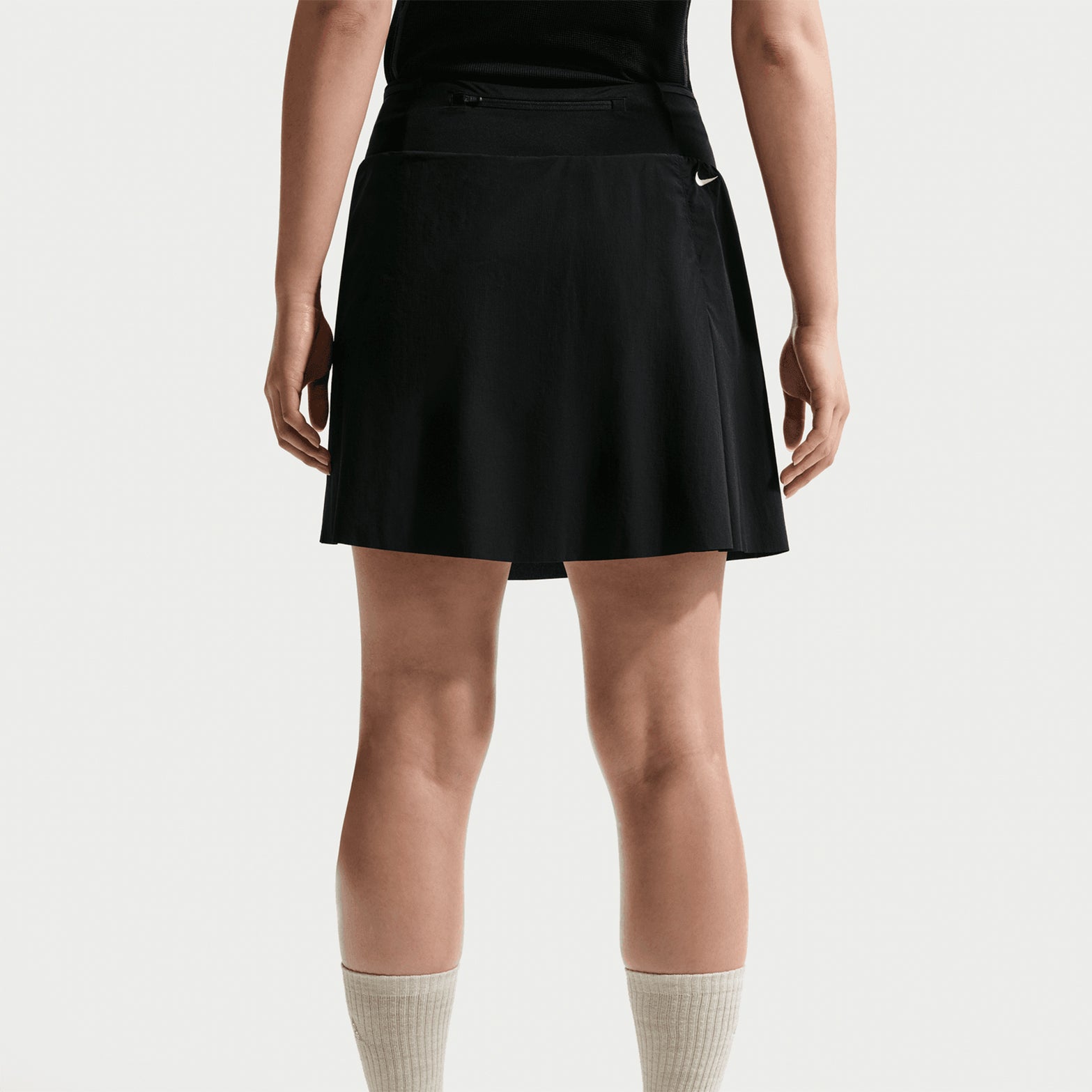 Women's Nike ACG High Stakes Skort Black Black Summit White back view on female trail runner showing zippered back pocket with stretch-woven construction and UV protection for mountain activities