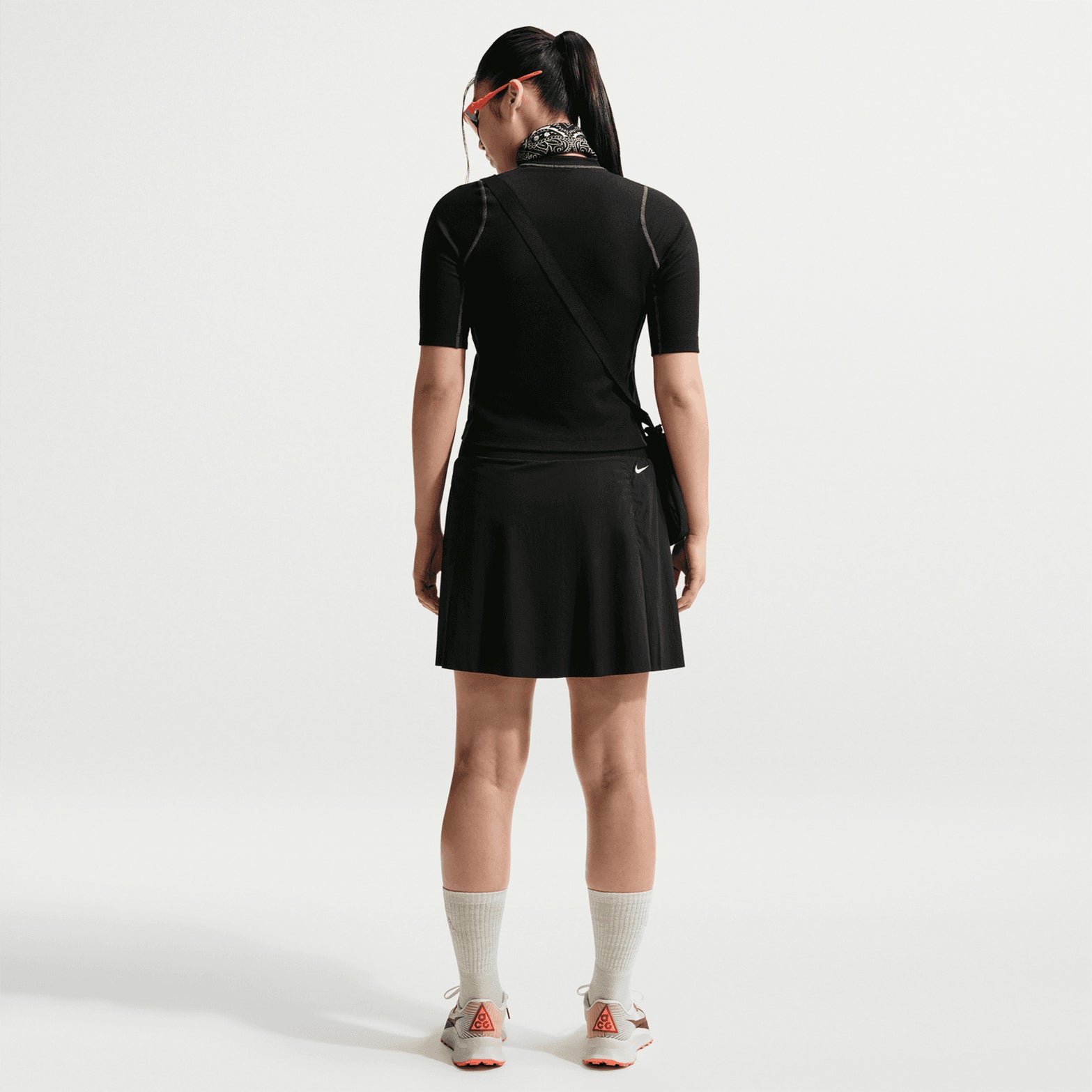 Women's Nike ACG High Stakes Skort Black Black Summit White back full body view on female trail runner showing zippered back pocket with lightweight stretch-woven construction and wide stretchy waistband for comfortable mountain hiking