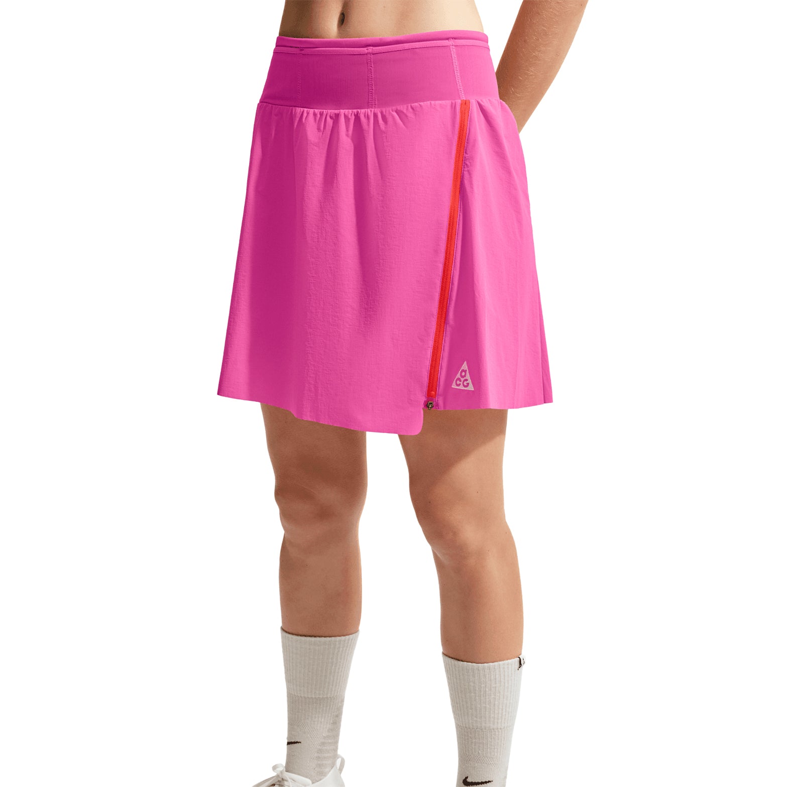 Women's Nike ACG High Stakes Skort Desert Pink Light Crimson Summit White front view on female trail runner showing stretch-woven outer with wide stretchy waistband and built-in knit shorts for comfortable hiking