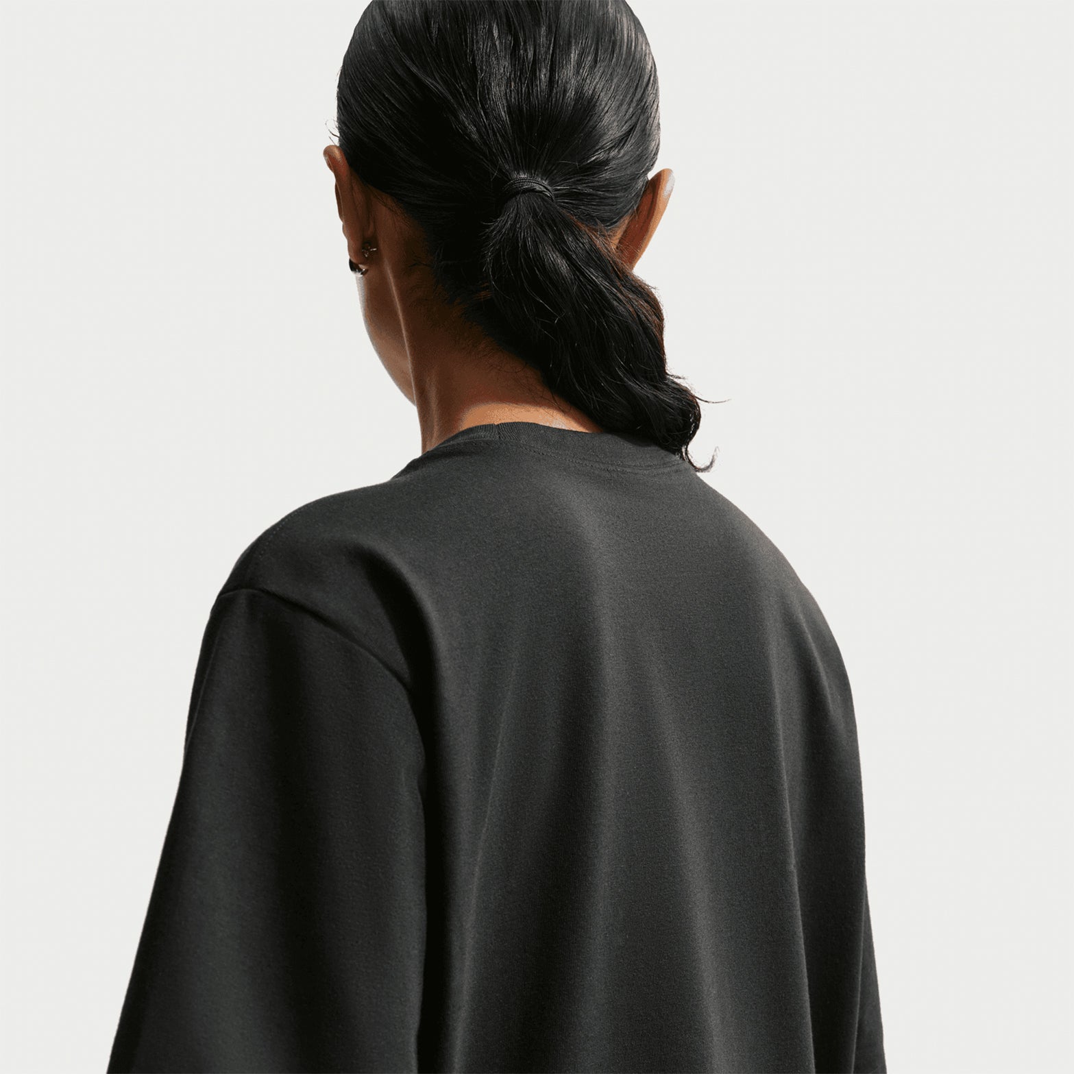 Nike ACG Tee women's in Black / Summit White — back view worn on model showing black loose-fit knit construction with summit white accent detailing and relaxed roomy fit