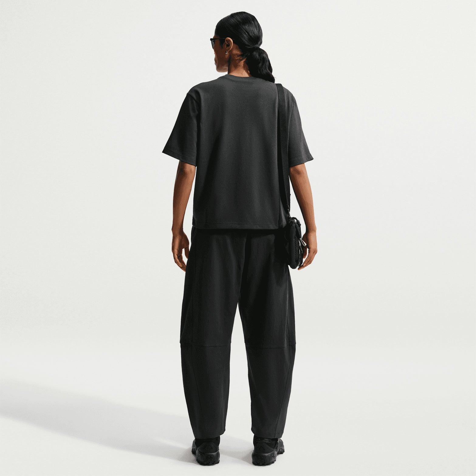 Nike ACG Tee women's in Black / Summit White — full body back view worn on model showing black loose-fit knit tee with summit white accent detailing and generous roomy cut for outdoor readiness