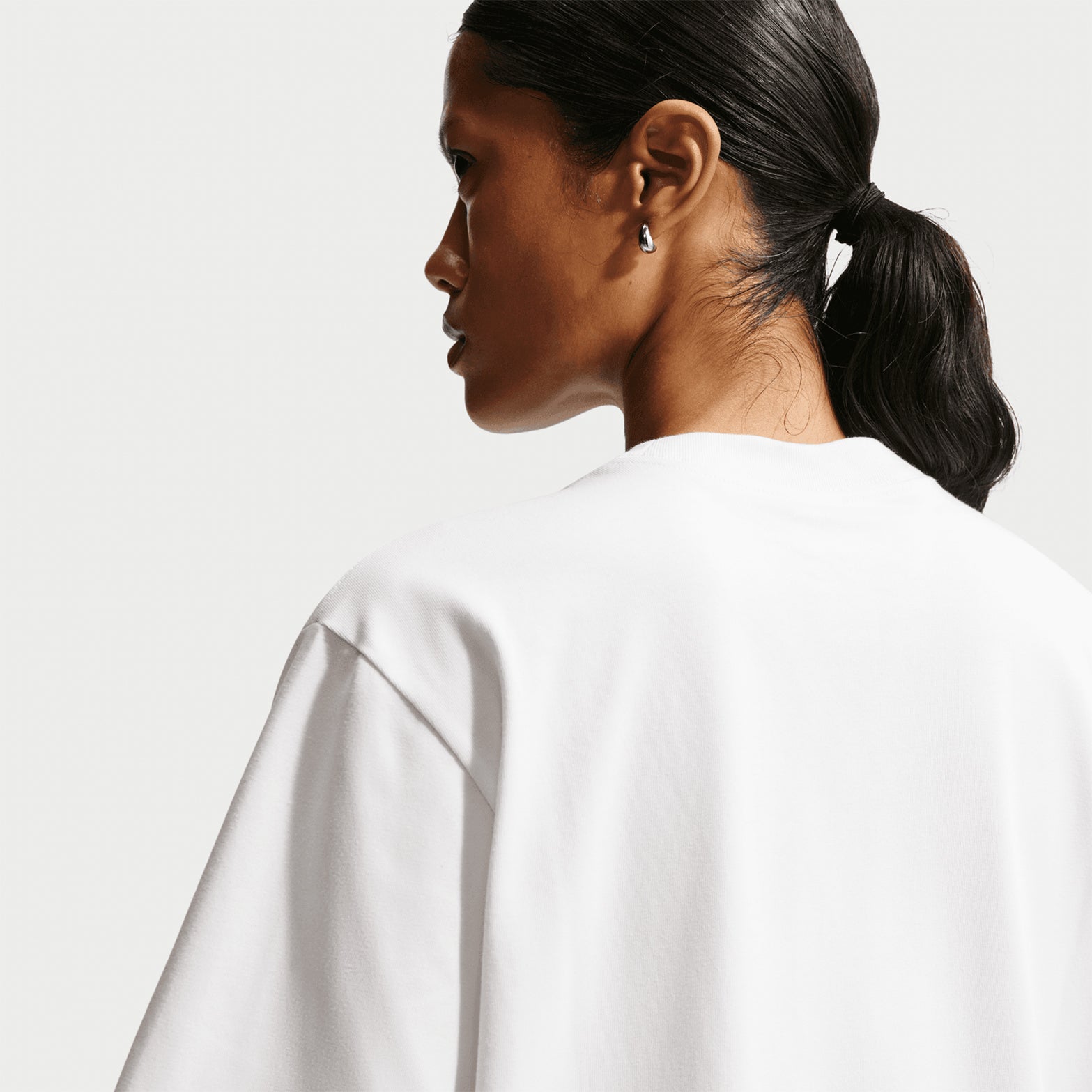 Nike ACG Tee women's in Summit White / Black — back view worn on model showing summit white loose-fit knit construction with black accent detailing and relaxed roomy fit