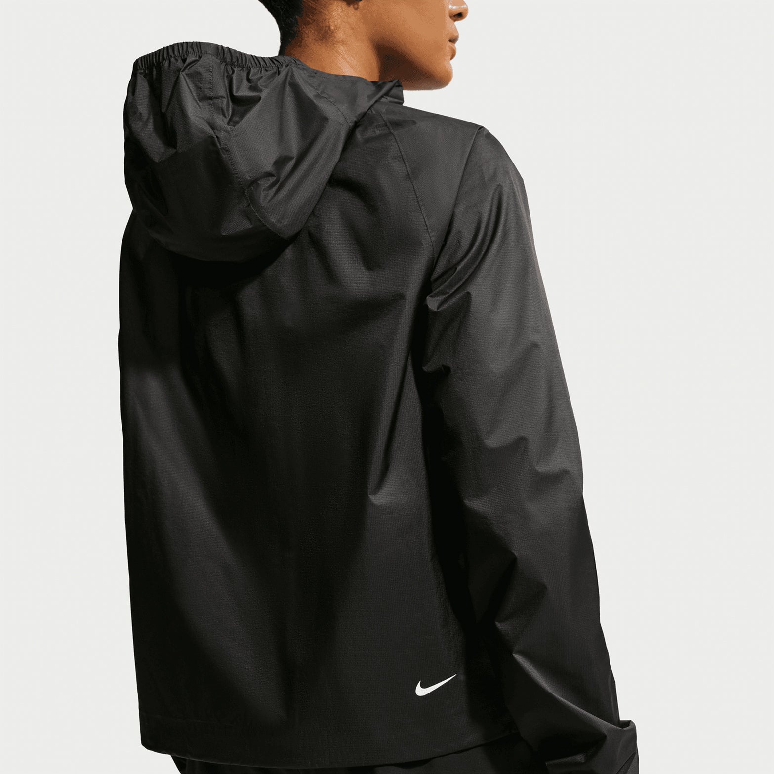 Women's Nike ACG Trailwind Storm-FIT ADV Jacket Black Summit White back view showing back vents for breathability with sealed seams and packable interior back pocket for trail running