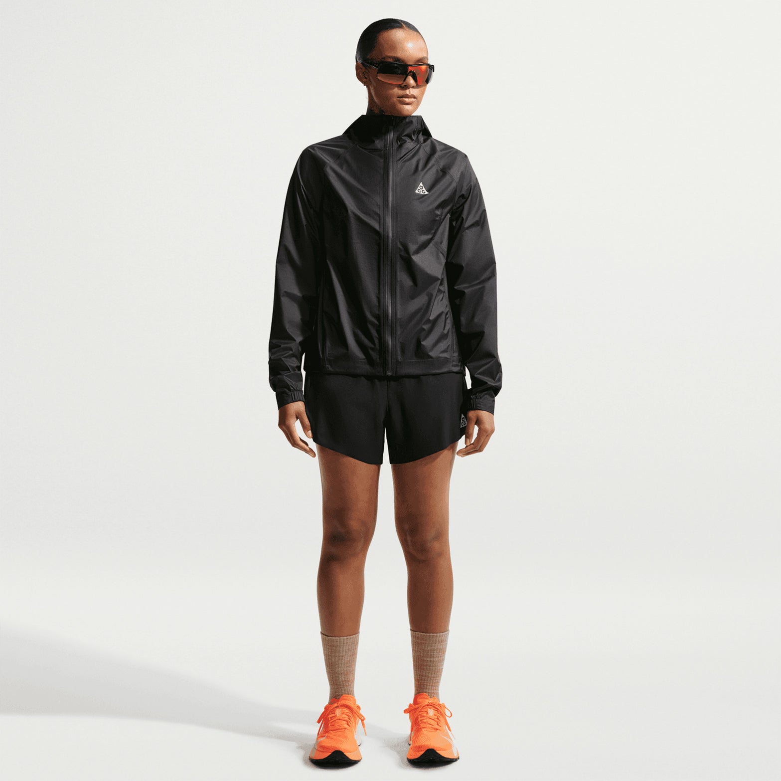 Women's Nike ACG Trailwind Storm-FIT ADV Jacket Black Summit White full body view on female trail runner showing ultra-lightweight Storm-FIT ADV waterproof construction with bungee-adjustable hood for unpredictable trail conditions