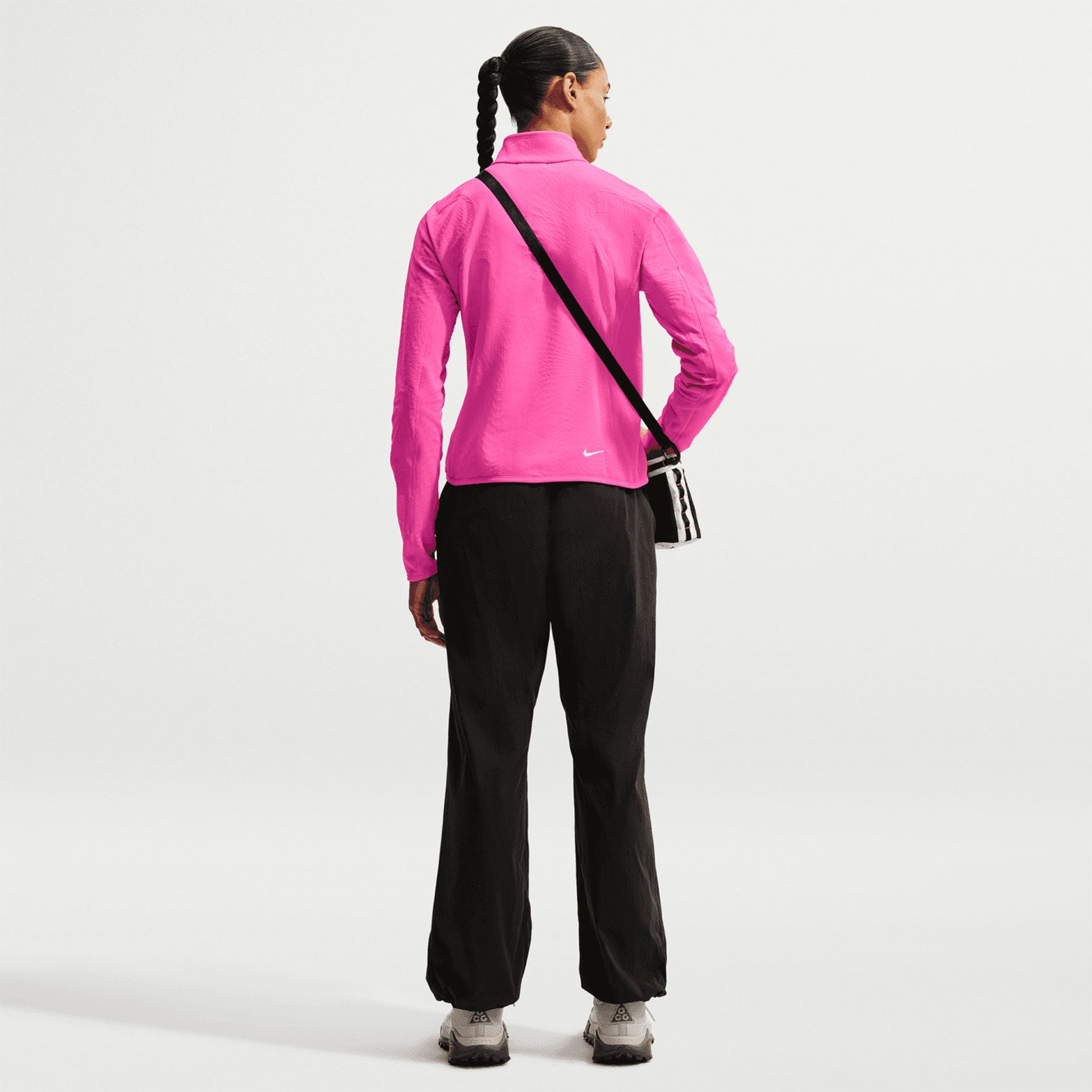 Women's Nike ACG Wolf Grid Therma-FIT 1/2 Zip Top Desert Pink Light Crimson Summit White full body back view on female trail runner showing grid-back fleece with Therma-FIT technology, flat seam shoulder panels and elastic hem for warmth and breathability during outdoor adventures