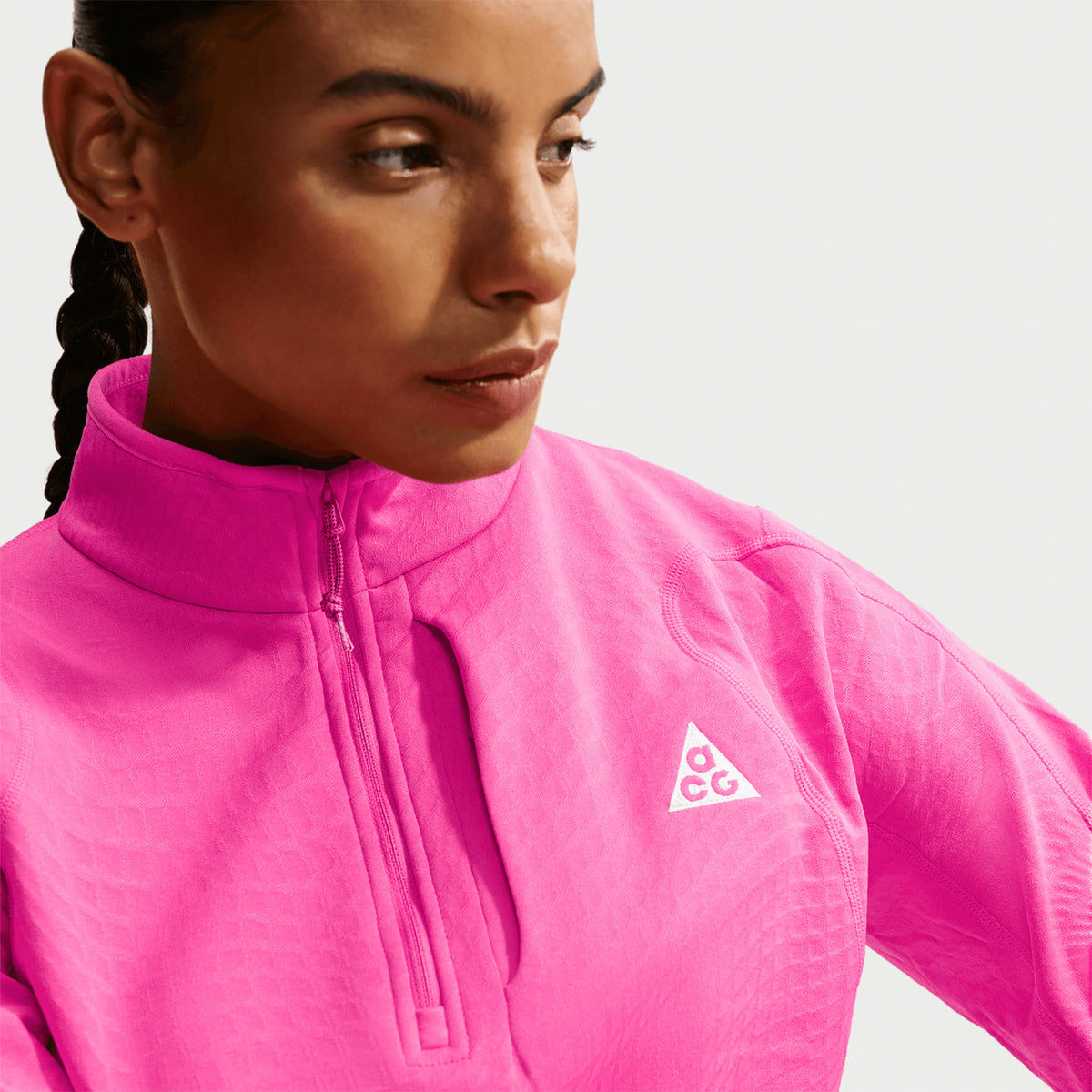 Women's Nike ACG Wolf Grid Therma-FIT 1/2 Zip Top Desert Pink Light Crimson Summit White close-up of embroidered ACG logo with checkerboard grid fleece and Therma-FIT moisture-wicking construction