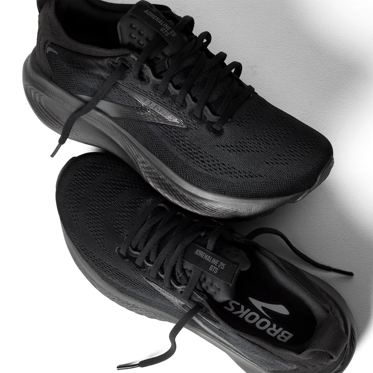 A pair of black Brooks Adrenaline GTS 23 running shoes, shown from above against a white background, with one shoe overlapping the other.