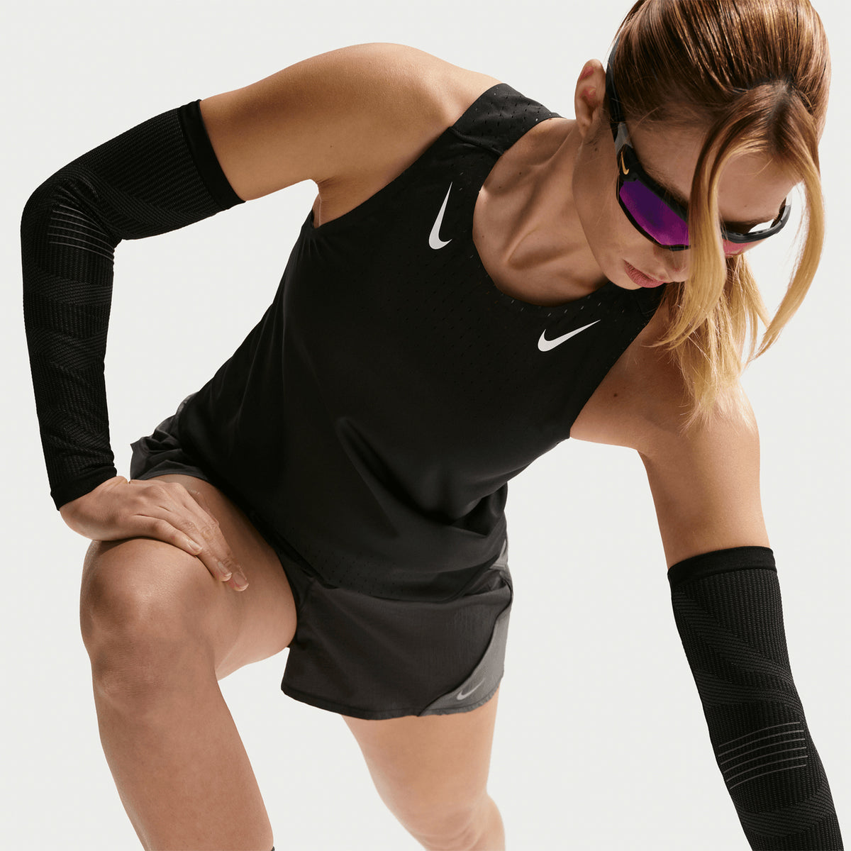 Nike AeroSwift Dri-FIT ADV Women's Running Vest in Black / White — front view worn on model showing cropped slim-fit silhouette, black Dri-FIT ADV fabric and white detailing in motion
