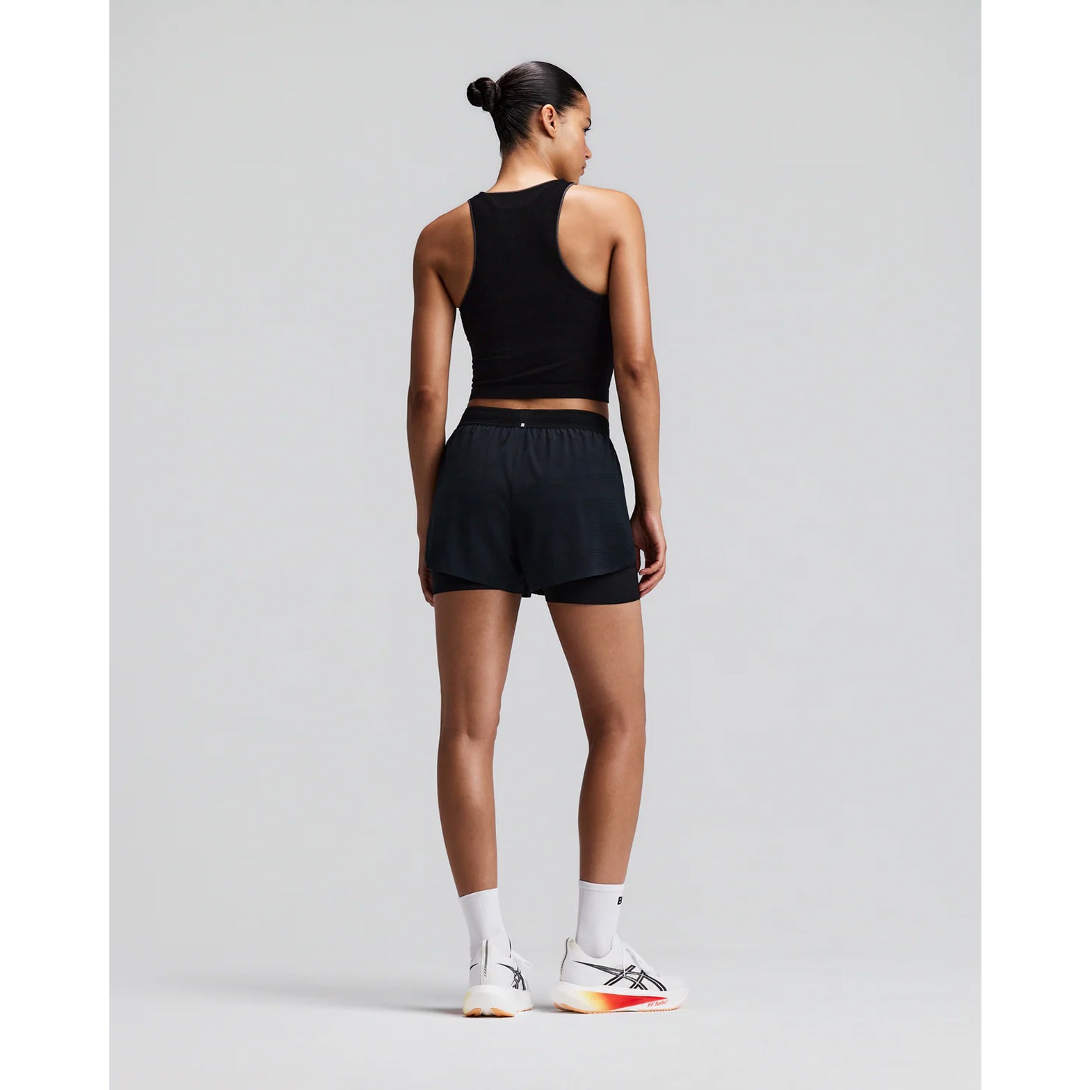 Women's Bandit CoolGrid 2-in-1 Run Short Black back full body view on female runner showing GripDot hem grip with reflective centre back branding and CoolGrid breathable construction
