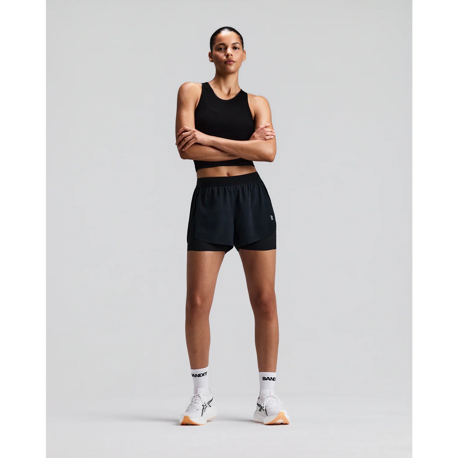 Women's Bandit CoolGrid 2-in-1 Run Short Black front full body view on female runner showing 2-in-1 CoolGrid outer with moisture-wicking liner and six-pocket system for road running and racing