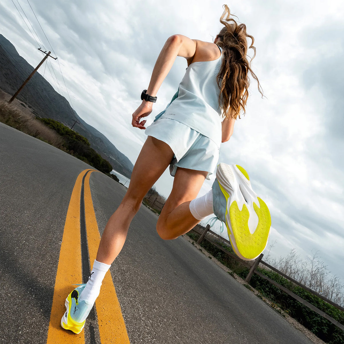 Women's PUMA Deviate NITRO Elite 4 Running Shoes Blue Yellow worn by runner showing PUMAGRIP all-surface traction outsole and NITROFOAM Elite midsole in motion