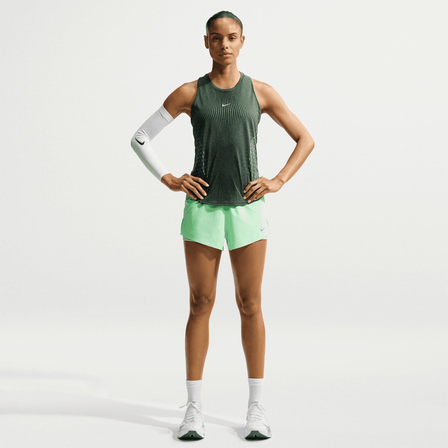 Women's Nike Dri-FIT Aeroswift Running Tank Black Light Green Spark Reflective Silver front full body view on female runner showing lightweight Aero-FIT construction with curved hem for peak breathability during warm weather running