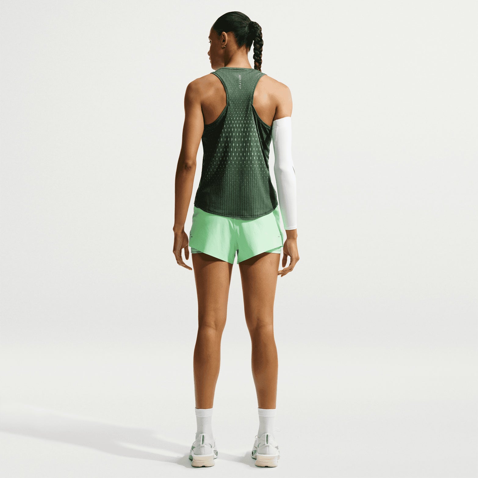 Women's Nike Dri-FIT Aeroswift Running Tank Black Light Green Spark Reflective Silver back full body view on female runner showing Aero-FIT airflow technology with reflective details and curved hem for breathable comfortable running