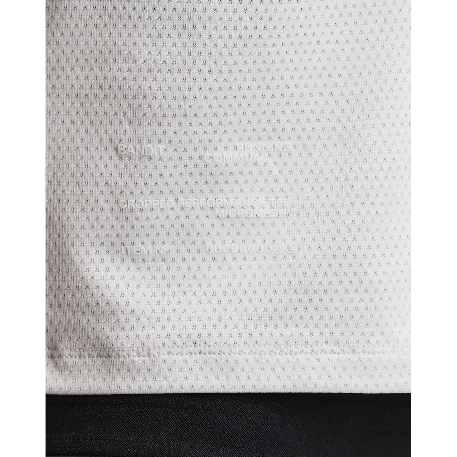 Women's Bandit Micromesh Cropped Run Tee Plaster close-up of hem showing subtle two-tone Bandit logo with reflective details for low-light visibility during running
