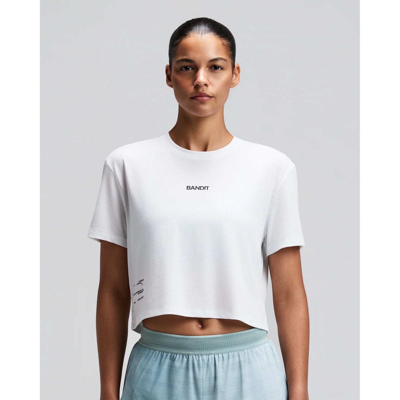 Women's Bandit Micromesh Cropped Run Tee White front view on female runner showing boxy cropped fit with crew neckline and breathable Micromesh construction for running and training