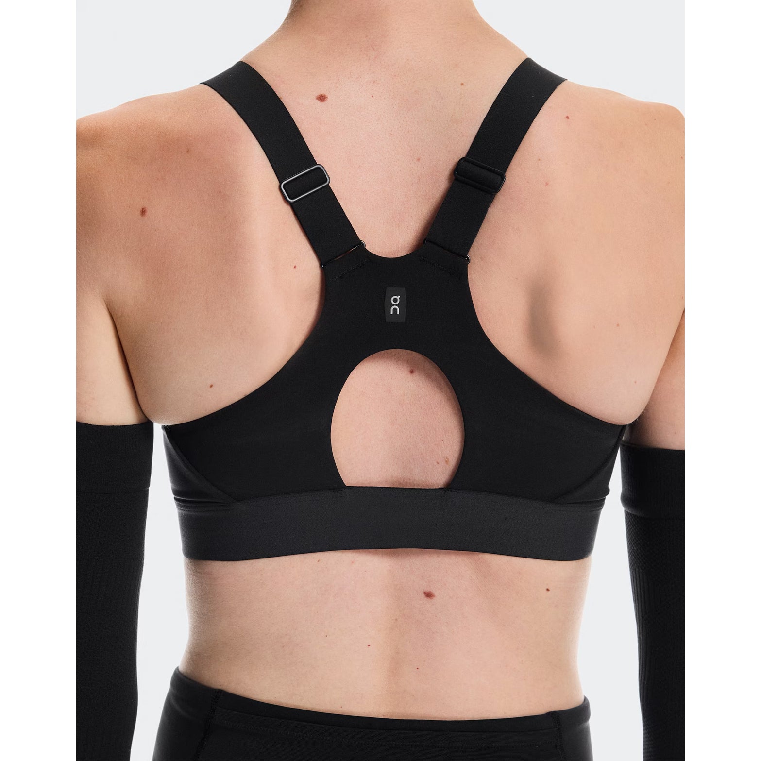 Women's On Performance Bra Black back view on female runner showing breathable mesh racerback inserts for airflow and back-positioned strap adjusters