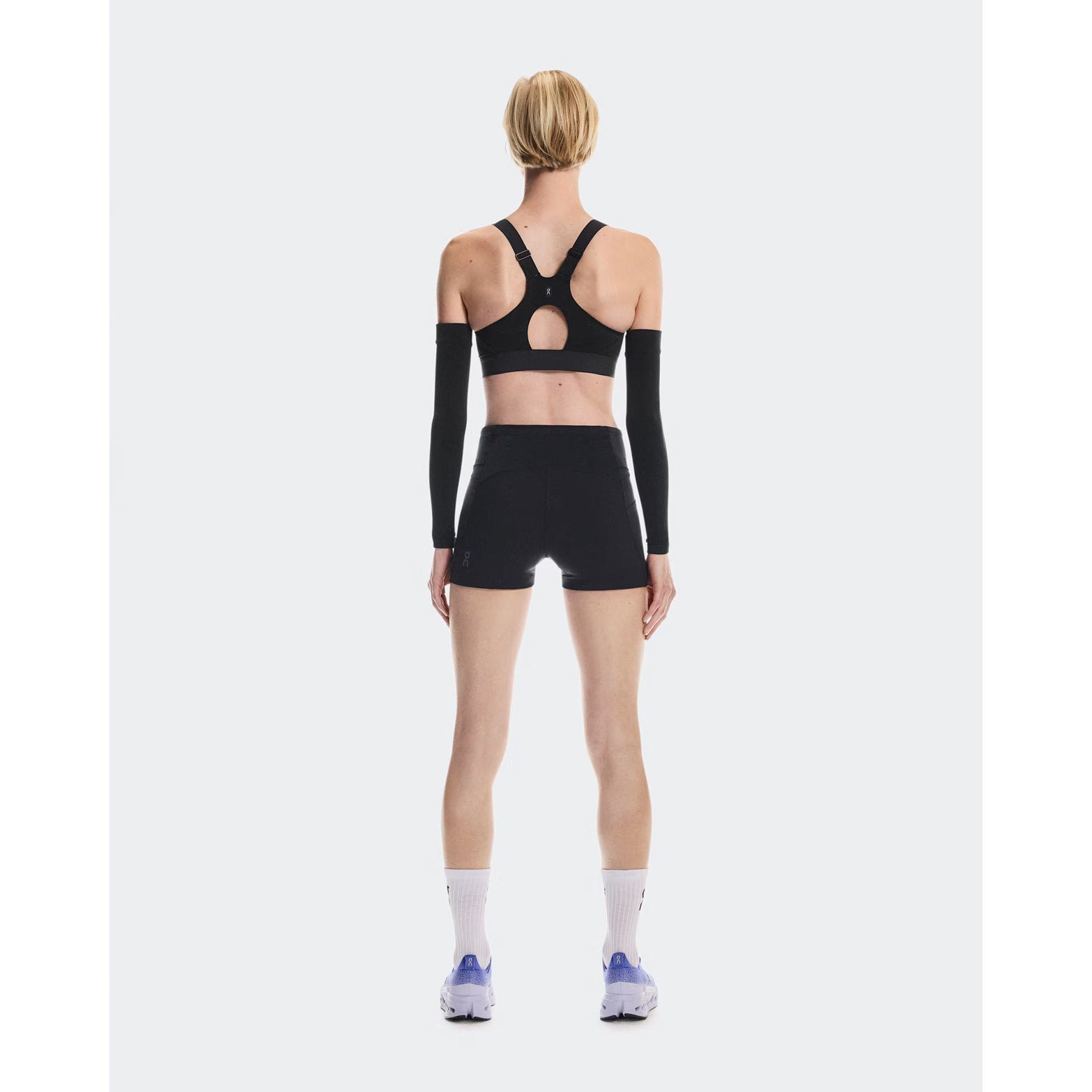 Women's On Performance Bra Black full body back view on female runner showing mesh racerback inserts for breathability and adjustable straps with back-positioned adjusters for comfort