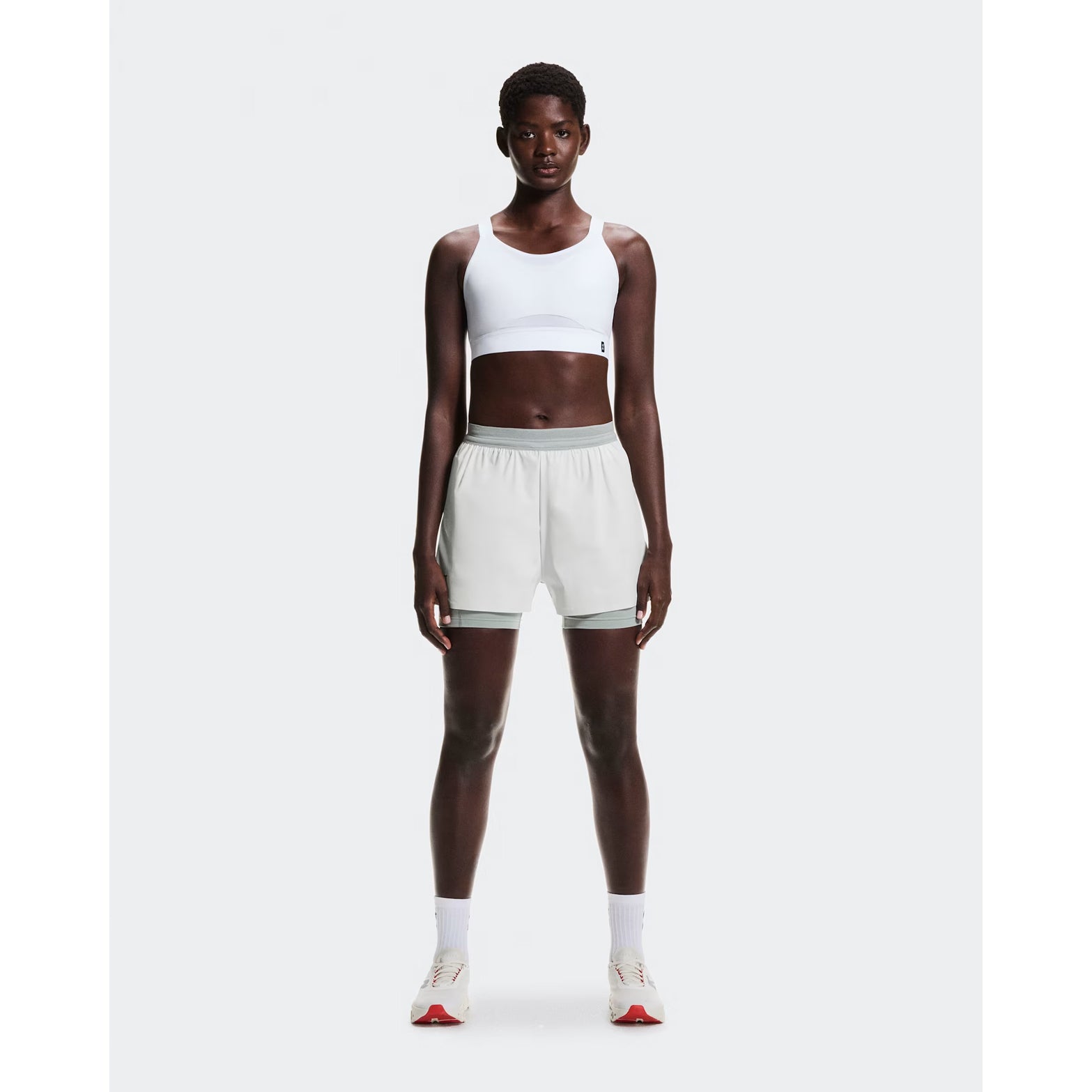Women's On Performance Bra White full body front view on female runner showing medium support pull-on design with On DryTec technology for moisture management