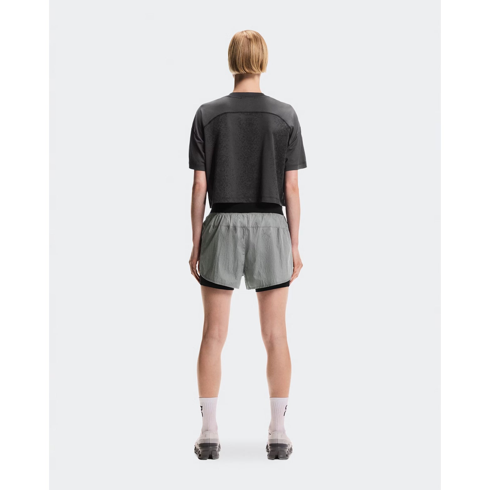 Women's On Performance Volt Shorts Glacier full body back view on female runner showing additional back pocket storage and water-repellent iridescent outer layer