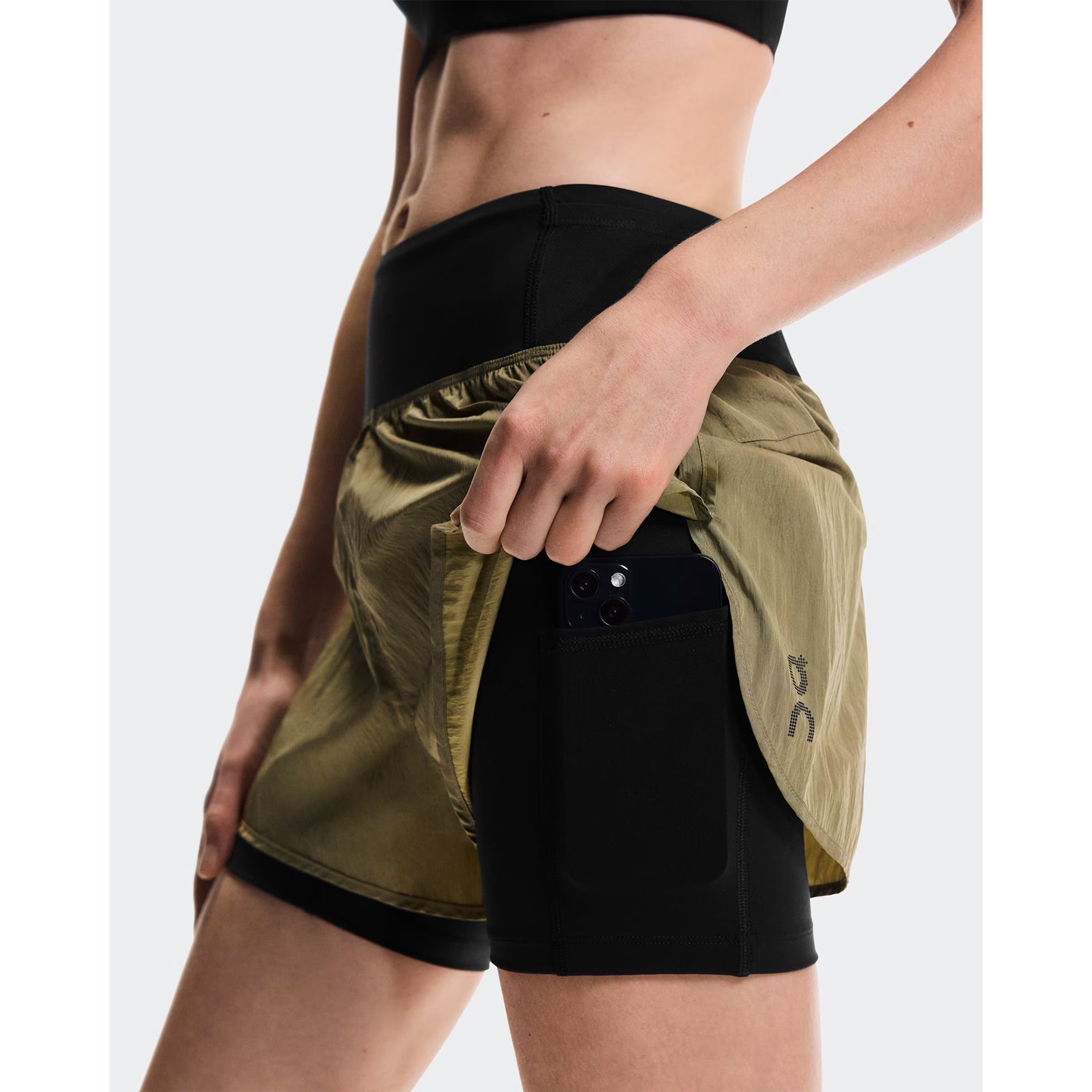 Women's On Performance Volt Shorts Safari side view on female runner showing dual-layer construction with windproof iridescent outer, four-way stretch inner tights, moisture-wicking On DryTec technology & phone pocket