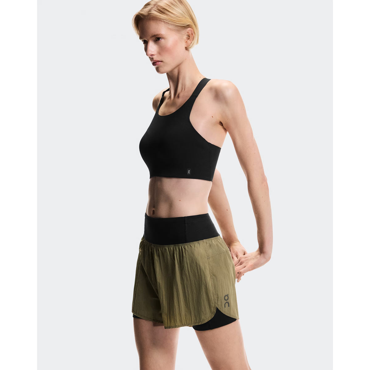 Women's On Performance Volt Shorts Safari side view on female runner showing dual-layer construction with windproof iridescent outer, four-way stretch inner tights and moisture-wicking On DryTec technology
