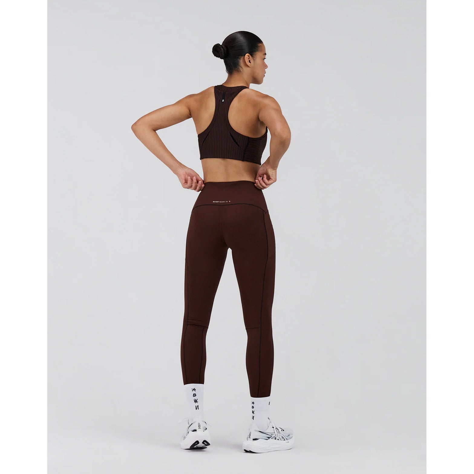 Women's Bandit Stamina-V High Waist Leggings full body back view on female runner showing comprehensive pocket system with 3 phone and 4 gel pockets plus pop-colour seaming