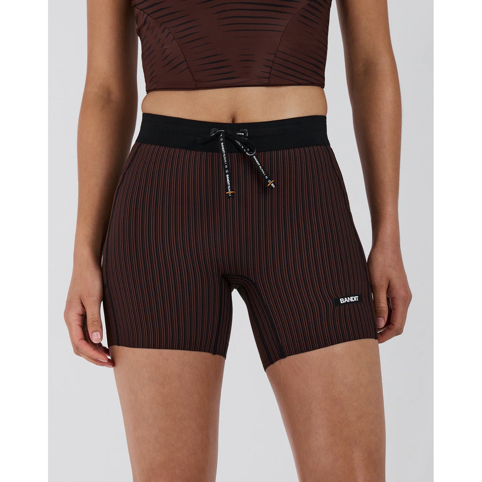 Women's Bandit Striped Cadence 5 Inch Compression Shorts Cacao Black front view on female runner showing no front rise seam, custom anti-chafe waistband and 5 inch inseam