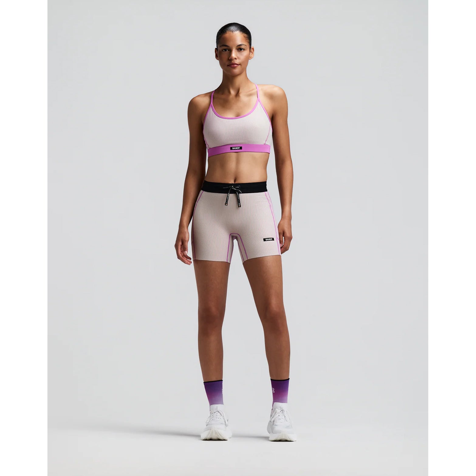 Women's Bandit Striped Cadence 5 Inch Compression Shorts Plaster Orchid front full body view on female runner showing 5-inch inseam with ultra-compressive ribbed knit and five-pocket storage system for racing and marathon training
