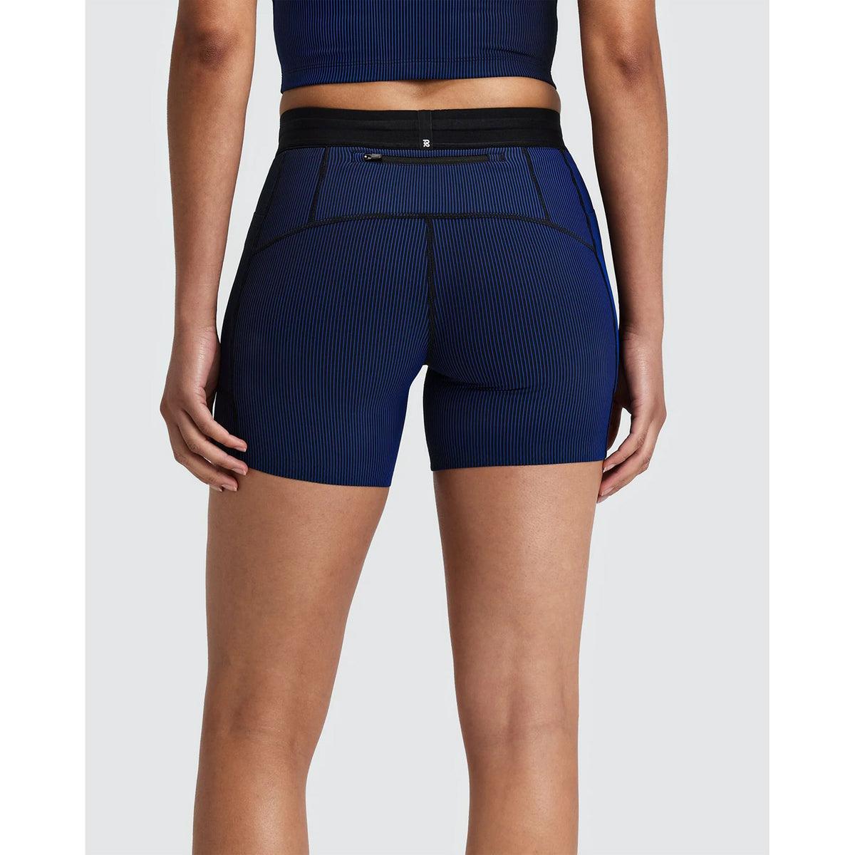 Rear view of Women’s Striped Cadence 5″ Compression Shorts Black / Bauhaus Blue featuring a black waistband and a zippered pocket at the back.