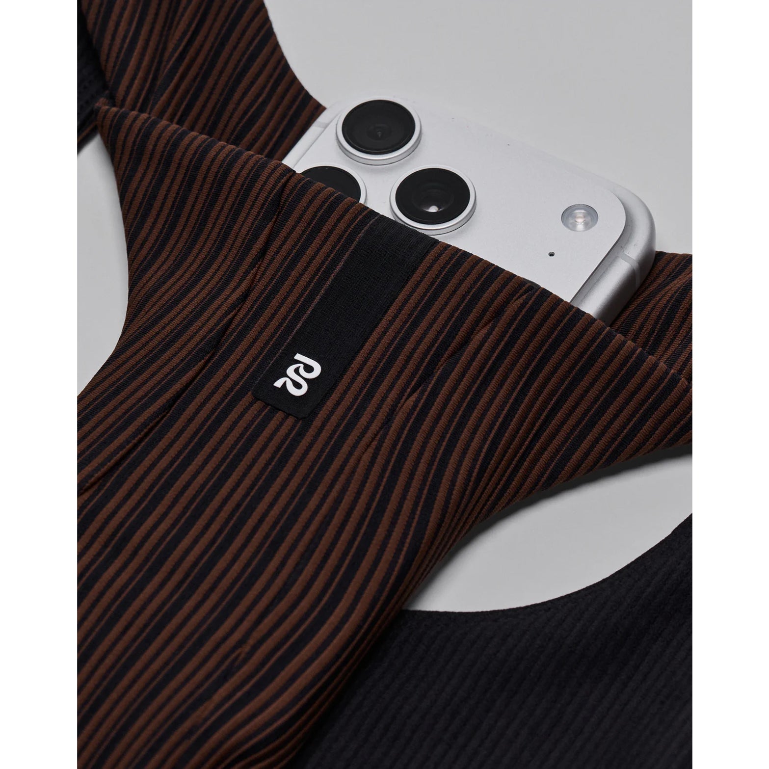 Bandit Striped Cadence Longline Bra women's in Cacao / Black — closeup showing waterproof phone pocket detail within the cacao and black striped ribbed knit construction