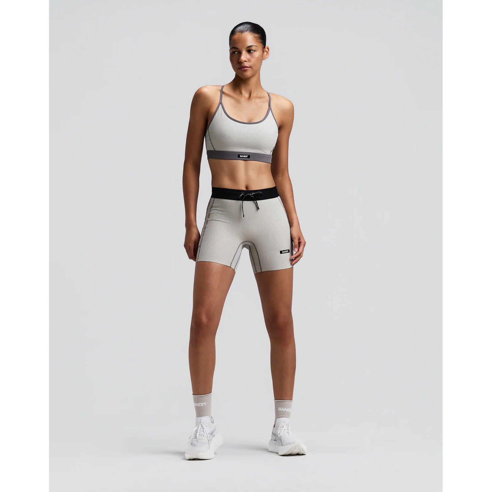 Women's Bandit Striped Cadence Strappy Bra Plaster Slate front full body view on female runner showing adjustable straps with Striped Cadence ribbed compression and three-pocket system for road running and racing