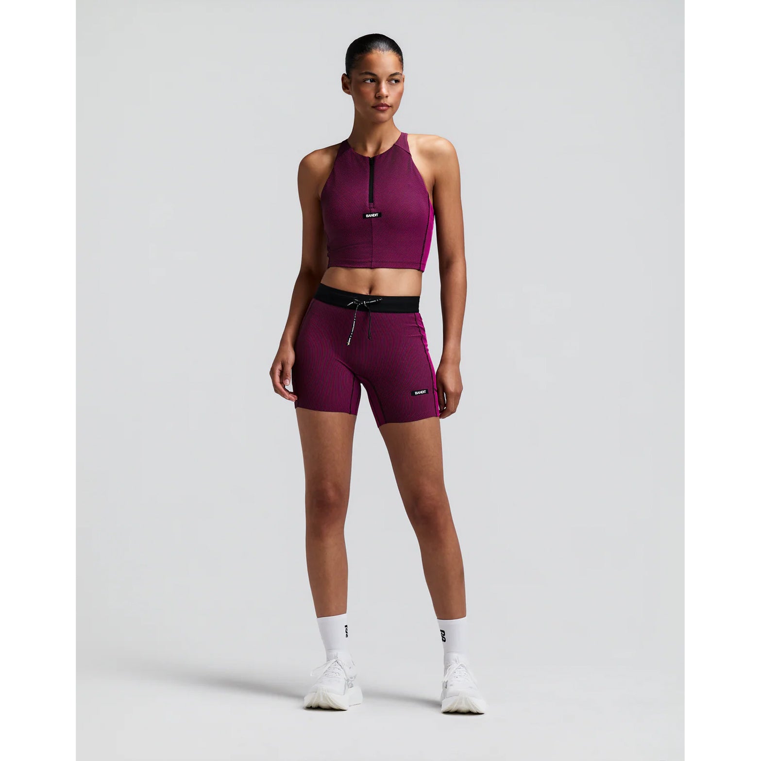 Women's Bandit Striped Cadence Zip Front Race Crop Espresso Azalea front full body view on female runner showing halter fit with zip front, Striped Cadence ribbed compression and seven-pocket system for road running and racing