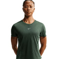 A person stands facing forward, wearing a fitted Nike Women’s Swift Aero-FIT Running Tee in Black / Light Green Spark with subtle stripes and short sleeves, against a plain white background.