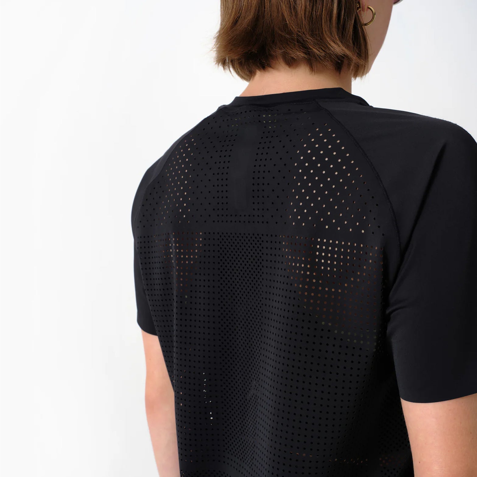 Women's Raide Thermal Dispersion Tee Black back view on female runner showing densely perforated centre back heat zone with body-mapped laser-cut ventilation for evaporative cooling during sustained effort