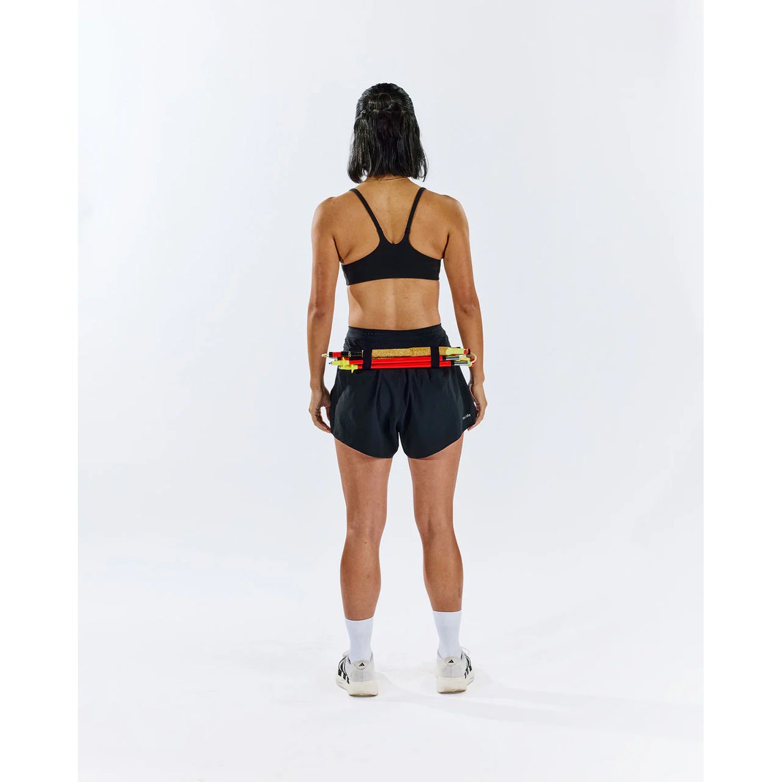 Raide TrailTech Short women's in Black — full body back view worn on model showing large rear pocket placement, zippered pocket detail and Toray DotAir outer construction in motion on trail