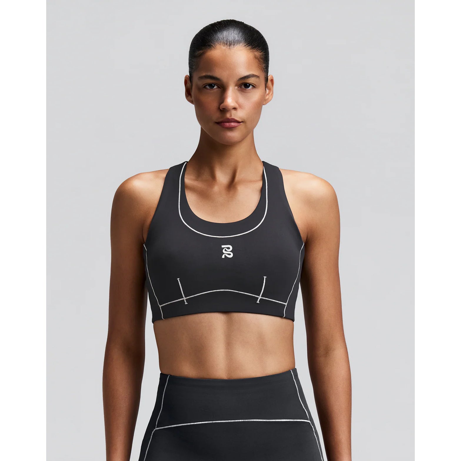 Women's Bandit Vanisher Pop Stitch Arco Run Bra Anthracite front view on female runner showing Vanisher sweat-hiding compression with Pop Stitch neckline detail and reflective front branding