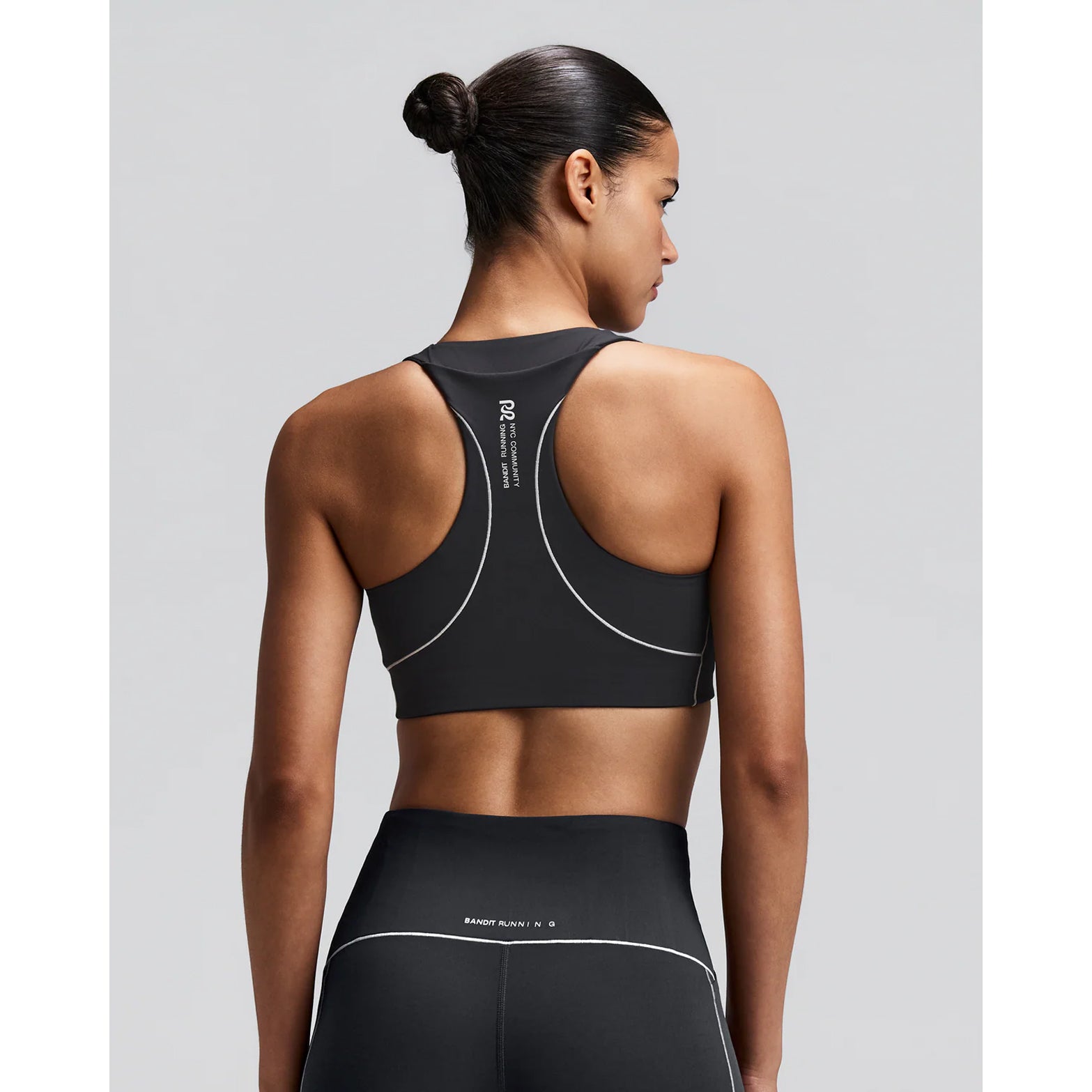 Women's Bandit Vanisher Pop Stitch Arco Run Bra Anthracite back view on female runner showing waterproof back phone pocket with reflective branding and Vanisher compression construction