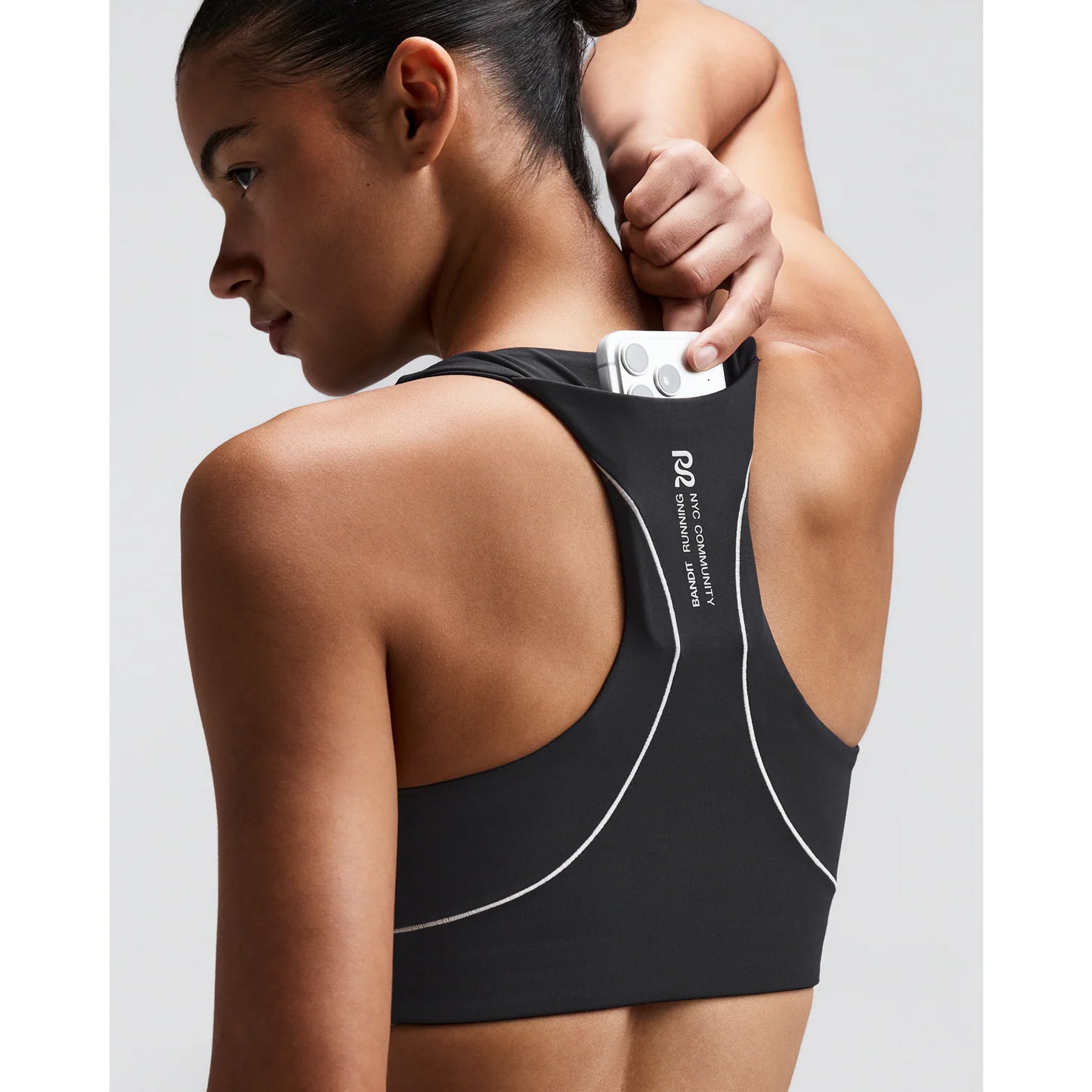 Women's Bandit Vanisher Pop Stitch Arco Run Bra Anthracite close-up of back showing waterproof phone pocket with reflective branding and Vanisher sweat-hiding compression construction