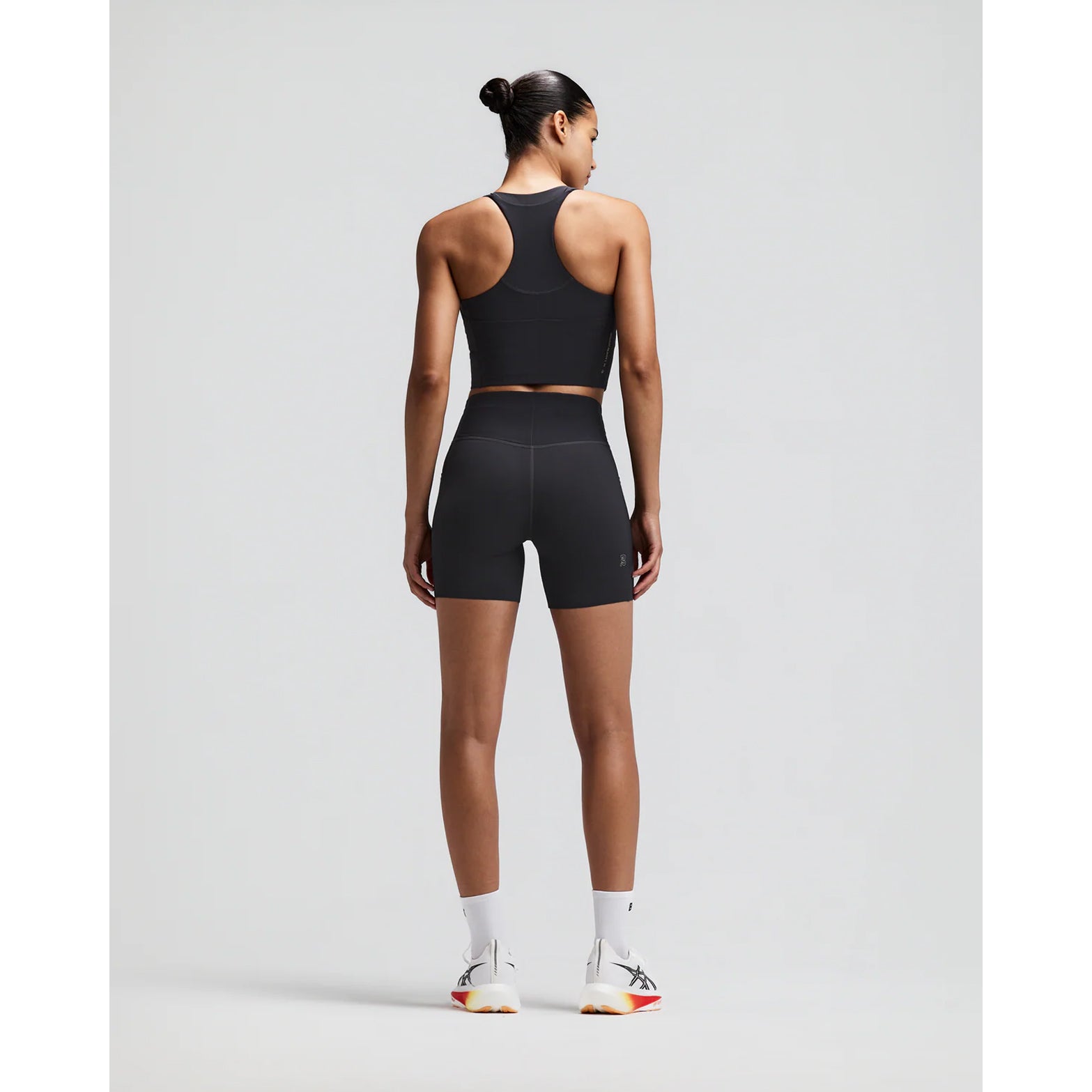 omen's Bandit Vanisher V-Neck Race Crop Top Anthracite back full body view on female runner showing Powermesh back panel with reflective branding and Vanisher compression construction for race day performance