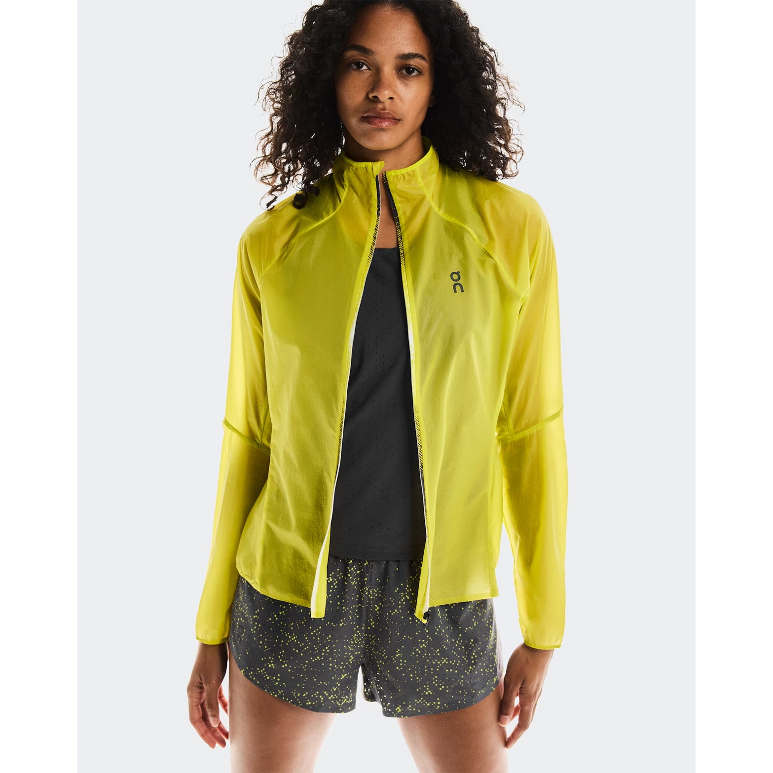 Women's On Zero Jacket Lime front view on female runner showing lightweight windproof construction with water-repellent surface and reflective elements